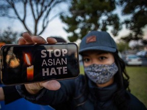 Julie Tran holds her phone during a candlelight vigil in Garden Grove, California, on March 17, 2021 to unite against the recent spate of violence targetting Asians and to express grief and outrage after yesterday's shooting that left eight people dead in Atlanta, Georgia, including at least six Asian women.