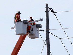 Utility workers use an aerial lift to check out power lines on Tecumseh Road West near Wellington Avenue, March 17, 2021.