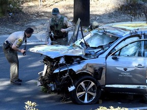 Los Angeles County Sheriff's Deputies inspect the vehicle of golfer Tiger Woods, who was rushed to hospital after suffering multiple injuries, after it was involved in a single-vehicle accident in Los Angeles, California, U.S. February 23, 2021.