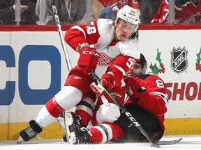 Will Butcher of the New Jersey Devils trips up Tyler Bertuzzi of the Detroit Red Wings during the second period at the Prudential Center on November 17, 2018 in Newark, New Jersey.