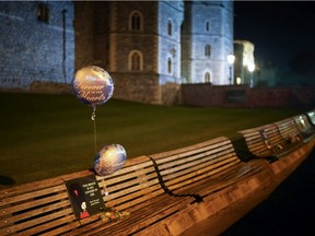 Flowers and balloons are placed on an empty bench outside Windsor Castle on the eve of the funeral of Prince Philip, Duke Of Edinburgh on April 16, 2021, in Windsor, United Kingdom.