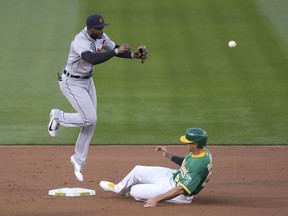 Niko Goodrum of the Detroit Tigers throws to first base while leaping over Matt Olson of the Oakland Athletics in the first inning at RingCentral Coliseum on April 16, 2021 in Oakland, California. Matt Chapman was safe on the play at first base.