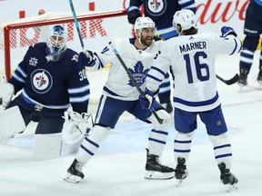 Maple Leafs forward Nick Foligno (centre) congratulates Mitch Marner (right) on his goal past Jets goaltender Laurent Brossoit during NHL action in Winnipeg, Thursday, April 22, 2021.