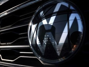 The storage facility auto tower of German carmaker Volkswagen is reflected in a VW logo at the company's headquarters in Wolfsburg, northern Germany on March 26, 2021.