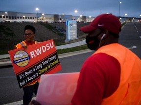 (FILES) In this file photo taken on March 27, 2021, Union organizers Syrena (L) and Steve (no last names given) wave to cars exiting an Amazon fulfillment center in Bessemer, Alabama. - A contentious unionization drive at an Amazon warehouse in Alabama failed as a vote count on April 9, 2021, showed a wide majority of workers rejecting the move. In a vote count seen online, National Labor Relations Board officials counted more than 1,608 "no" votes shortly before 1500 GMT, representing a majority of the 3,215 ballots cast. Slightly more than 600 votes favored the unionization effort organized by the Retail, Wholesale and Department Store Union.