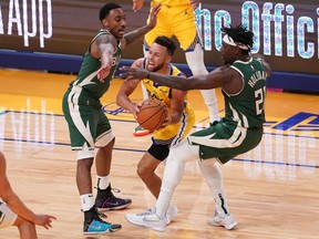 \Golden State Warriors guard Stephen Curry attempts to pass the ball between Milwaukee Bucks guard Jeff Teague and guard Jrue Holiday in the fourth quarter at the Chase Center.