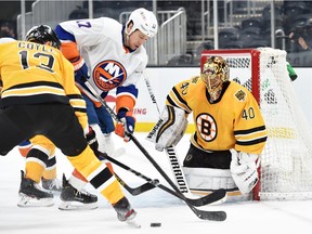 Boston Bruins center Charlie Coyle battles for the puck with New York Islanders left wing Matt Martin in front of goaltender Tuukka Rask during the third period at TD Garden.