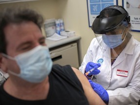 Jasjit Garcha, pharmacist and associate/owner at Shoppers Drug Mart on Huron Church Road, gives an AstraZeneca COVID-19 vaccine shot to Stephen Romanow on April 9, 2021.