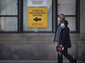 A couple walk past the COVID-19 vaccination centre at the University of Windsor's Windsor Hall, on Tuesday, April 6, 2021.