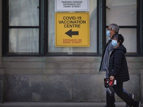 A couple walks past the COVID-19 vaccination centre at the University of Windsor's downtown Windsor Hall.
