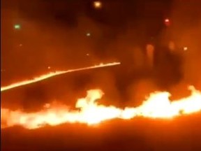 A screengrab from video shows people pouring some sort of flammable substance in a circle on a road before setting it on fire.