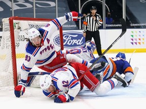 Brendan Smith and Mika Zibanejad of the New York Rangers fall defending against Anthony Beauvillier of the New York Islanders during the second period at the Nassau Coliseum on May 01, 2021 in Uniondale, New York.