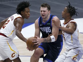 Luka Doncic of the Dallas Mavericks drives to the basket against Isaac Okoro of the Cleveland Cavaliers and Collin Sexton of the Cleveland Cavaliers in the second quarter at American Airlines Center on May 07, 2021 in Dallas, Texas.