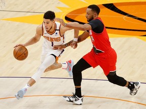 Devin Booker of the Phoenix Suns drives the ball against Norman Powell of the Portland Trail Blazers during the second half of the NBA game at Phoenix Suns Arena on May 13, 2021 in Phoenix, Arizona.  The Suns defeated the Trail Blazers 118-117.