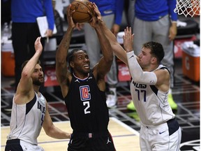 Kawhi Leonard #2 of the LA Clippers scores between Luka Doncic #77 and Maxi Kleber #42 of the Dallas Mavericks during a 127-121 Mavericks win in game two of the Western Conference first round series at Staples Center on May 25, 2021 in Los Angeles, California.