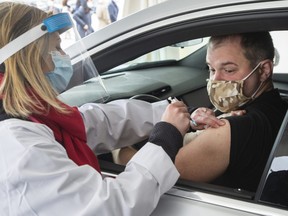 Alex Smirnov gets a COVID-19 vaccination from Annie Halinka Sanson at a demonstration of a drive-through vaccination site, Tuesday, May 4, 2021 in Montreal.