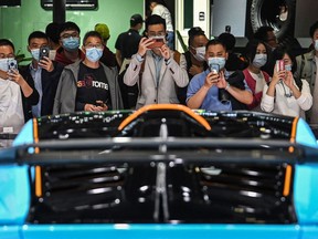 People use their mobile phones to take photos of a Lamborghini Huracan STO car during the 19th Shanghai International Automobile Industry Exhibition in Shanghai on April 21, 2021.