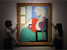 Gallery workers are shown April 22, 2021, with an artwork titled 'Femme assise près d'une fenêtre (Marie-Thérèse)' by Spanish painter Pablo Picasso during a photocall at Christies auction house in central London. "Woman sitting by a window (Marie-Therese)" sold Thursday for US$103.4 million at Christie's in New York, the auction house said. The painting, completed in 1932, was sold for $90 million, which rose to $103.4 million when fees and commissions were added, after 19 minutes of bidding, Christie's said.