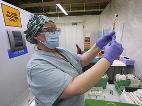 In this May 3, 2021, file photo, pharmacy technician Maryann Bakare draws a dose of the Pfizer-BioNTech vaccine at the St. Clair College SportsPlex field hospital. Local leaders are pushing Ottawa to facilitate bringing excess U.S. vaccines in Michigan to Canadian residents near the border.