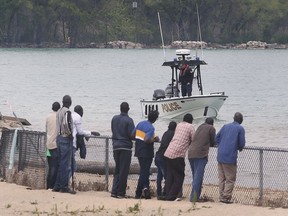 Friends and family members of a man who went missing while swimming Saturday at Sand Point Beach watch from the shoreline on Monday, May 24, 2021, as search efforts by police marine units continued.
