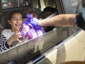 Mahmoud Elkadri, manager of the Rose City Islamic Centre, hands out goodie bags to Tasnim Alali, 10, during a drive-thru celebrating Eid al-Fitr, on Thursday, May 13, 2021.