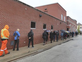 People wait in the rain on Monday, May 3, 2021 at a hot spot pop-up COVID-19 vaccine clinic at the St. Angela Centre and Hall on Erie Street in Windsor.