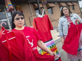 Tina Jacobs, left, executive director of the Can-Am Indian Friendship Centre, and Sheilina John, a volunteer, hold red dresses for Red Dress Day honouring missing and murdered indigenous women and girls, on Wednesday, May 5, 2021.