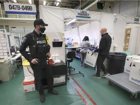 Extra sets of eyes guard every movement of Windsor's precious vaccine supplies. Here, pharmacist David Sinewitz transports a shipment of Pfizer COVID-19 vaccine doses at the St. Clair College SportsPlex mass vaccination site as a Windsor Police Service officer provides security. The photo was taken this month, but the Windsor Star had to agree not to specify the date.