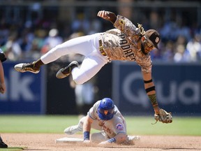 Billy McKinney of the New York Mets steals second base as Fernando Tatis Jr. of the San Diego Padres leaps over fielding the throw in the sixth inning at Petco Park on June 6, 2021 in San Diego, California. McKinney safely stole second base.