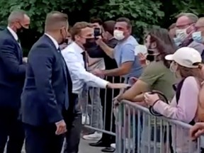 French President Emmanuel Macron speaks with a member of the public before he was slapped during a visit in Tain-L'Hermitage, France, in this still image taken from video on Tuesday, June 8, 2021.