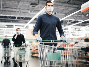 young man in a protective mask with a shopping cart