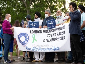 People hold a banner at the start of the multi-faith march to end hatred, on the site where a man driving a pickup truck struck and killed four members of a Muslim family in London, Ont., June 11, 2021.