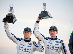 Roman De Angelis of Belle River (right) and co-driver Ross Gunn (left) hold up their trophies after competing in the GT Daytona class of the Detroit Grand Prix on June 12, 2021.