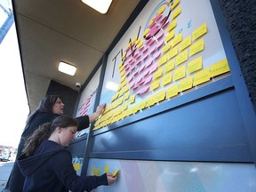 Lisa Valente and her daughter Lilyana Jardine put up positive Post-it notes on the windows of Trans Wellness Ontario in Windsor on June 22, 2021.