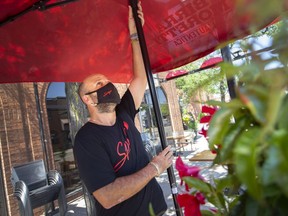 Chris Menard, a server at Spago trattoria and pizzeria on Erie Street East in Windsor, sets up an umbrella in preparation for patio dining on June 10, 2021.
