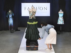 St. Clair College Fashion Design Technician program coordinator and professor Elaine Chatwood adjust a dress during the Virtual Atelier Fashion Show at the school on Tuesday, June 15, 2021. Due to pandemic restrictions a robot was used to showcase designs of graduating students.