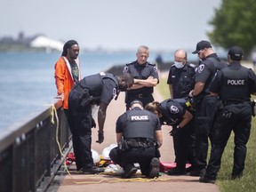 Several Windsor police officers intercept a man found swimming in the Detroit River east of the riverfront parking at Campbell Avenue, on Wednesday, June 23, 2021.