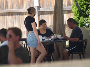 A waitress serves customers on the patio of The Thompson House in Windsor's Riverside area on June 11, 2021.