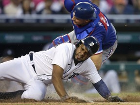 Catcher John Hicks of the Texas Rangers tumbles after tagging out Jeimer Candelario of the Detroit Tigers trying to score from second base in the seventh inning at Comerica Park on July 21, 2021, in Detroit, Michigan.