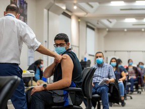 The team lead from Humber River Hospital's mobile vaccine clinic, Ruben Rodriguez, administers the first dose of the Moderna COVID-19 vaccine to an employee of pharmaceutical company Apotex, as part of the vaccination campaign, in Toronto, April 13, 2021.