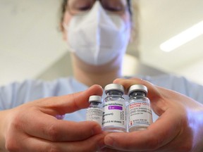 A woman wearing a mask shows three vials with different vaccines against COVID-19 by (left to right) Pfizer-BioNTech, AstraZeneca and Moderna in the pharmacy of the vaccination centre at the Robert Bosch hospital in Stuttgart, Germany, Feb. 12, 2021.