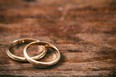 A pair of golden wedding rings on wooden background, copy space