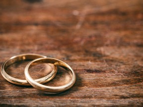 A pair of golden wedding rings on wooden background, copy space