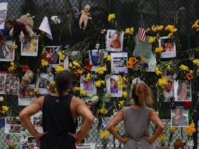 People look at a memorial that has pictures of some of the missing from the partially collapsed 12-story Champlain Towers South condo building in Surfside, Fla., Wednesday, July 7, 2021.
