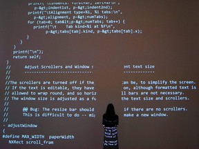 A person poses in front of a projection of source code during a media preview at Sotheby's on June 24, 2021, in New York, for Sotheby's NFT Auction of Sir Tim Berners-Lee "Source Code for the World Wide Web," which will be offered for sale as an NFT.