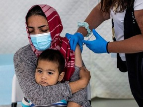 A migrant holds her baby as she receives a shot of the Johnson & Johnson vaccine against the coronavirus disease (COVID-19) in the Mavrovouni camp for refugees and migrants on the island of Lesbos, Greece, June 3, 2021.