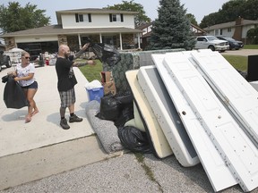 Susie and Craig Weir place flood damaged items at the front of their Maplewood Drive home in Lakeshore on Monday, July 19, 2021. The couple's finished basement was destroyed by flooding.