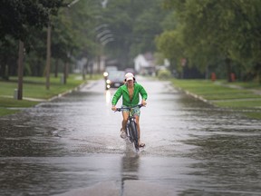 "Deluge." Windsor and Essex County remain under a special rainfall alert until Saturday. Here, Ethan Brett, 15, rides his bike through a flooded portion of Little River Blvd. in Tecumseh as heavy rain on Friday, July 16, 2021. Flooding has forced the closure of a number of stretches of local streets.