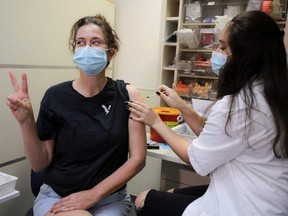 An Israeli woman poses for a picture as she receives a third shot of a COVID-19 vaccine as the country launches booster shots for over 40-year-olds, in Jerusalem, Friday, Aug. 20, 2021.