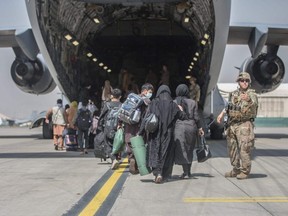 In this handout image courtesy of the U.S. Marine Corps, families begin to board a U.S. Air Force Boeing C-17 Globemaster III during an evacuation at Hamid Karzai International Airport, in Kabul, Afghanistan, Monday, Aug. 23, 2021.